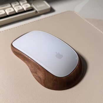 A close-up of an Apple Magic Mouse in a wooden stand, showcasing the sustainable, kiln-dried wood craftsmanship, hand-finished with non-toxic oils, and designed for ergonomic comfort.